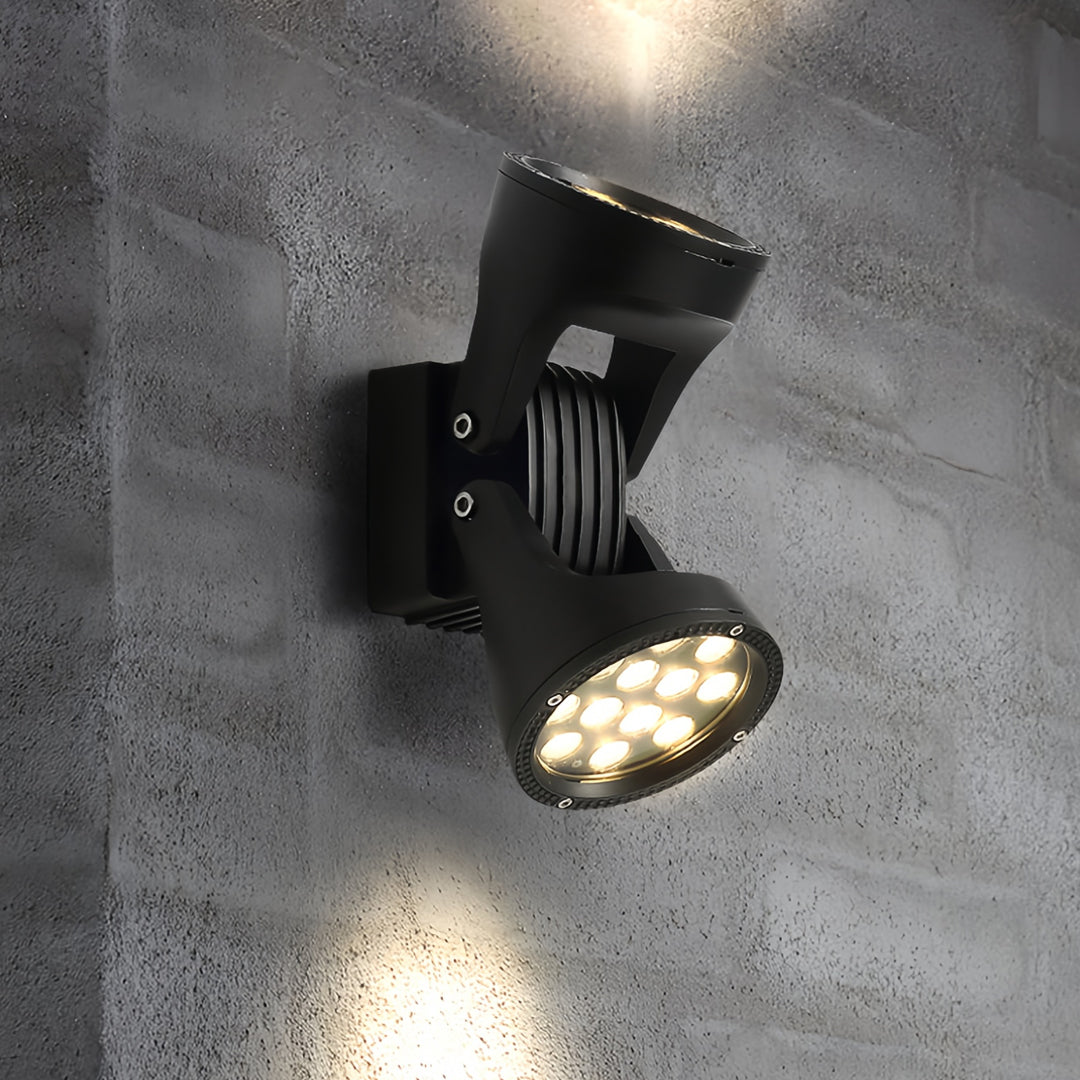 Modern adjustable two light wall sconce with spotlight-style beams illuminating a concrete wall.