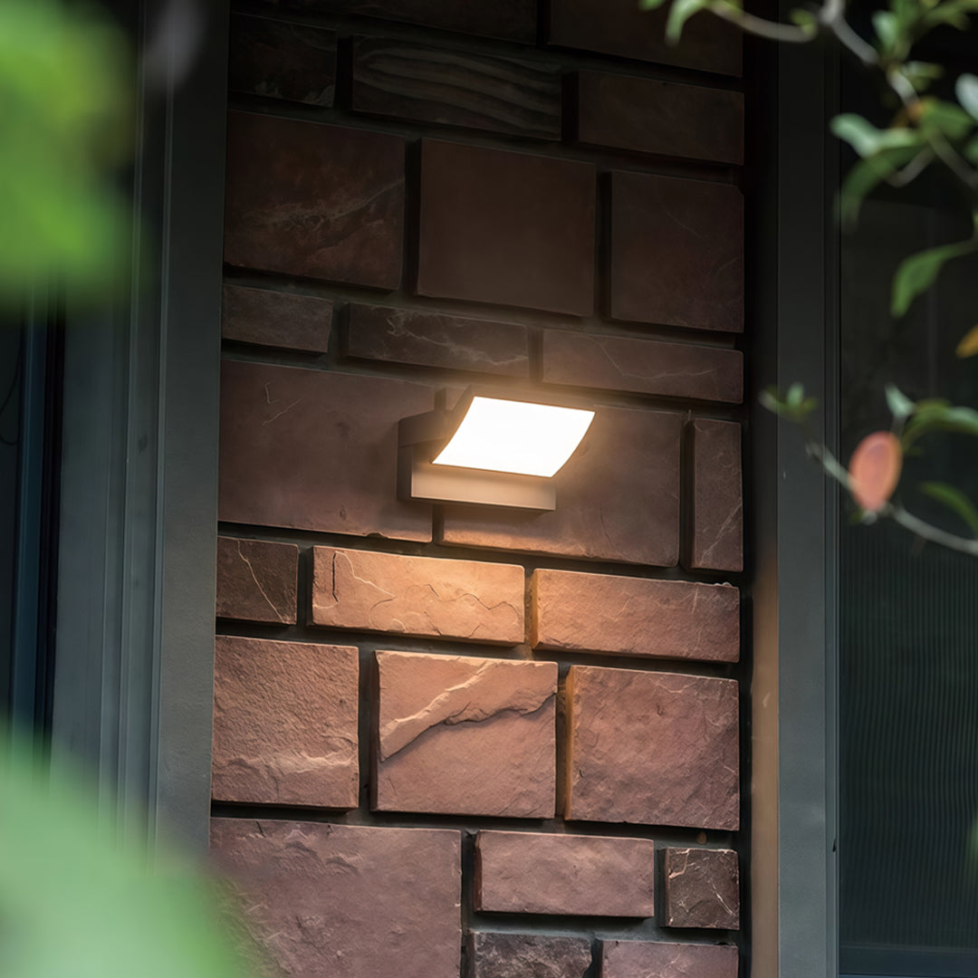 Compact adjustable wall light installed on a brick wall, providing focused warm illumination.