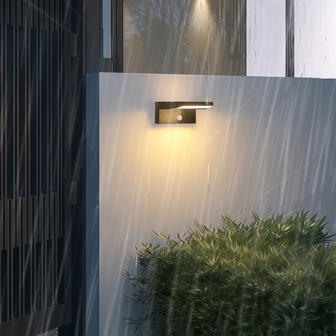 Adjustable wall light softly lighting a garden-side exterior wall with warm ambient glow.
