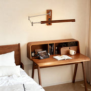 Adjustable wooden swing wall light mounted above a mid-century modern desk in a bedroom setting.
