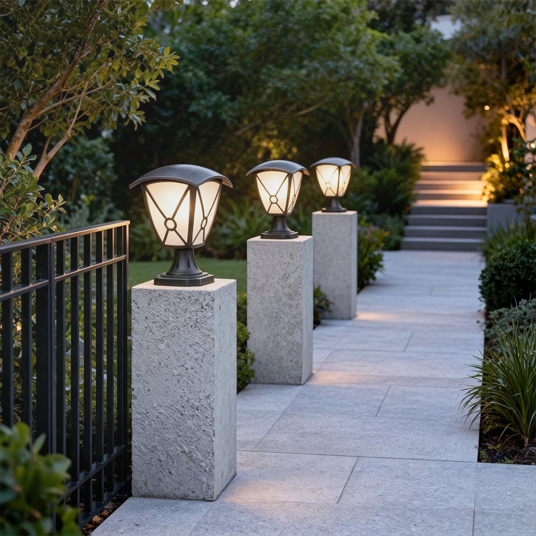 Aluminum pillar lights arranged along modern fence posts beside a paved garden walkway.