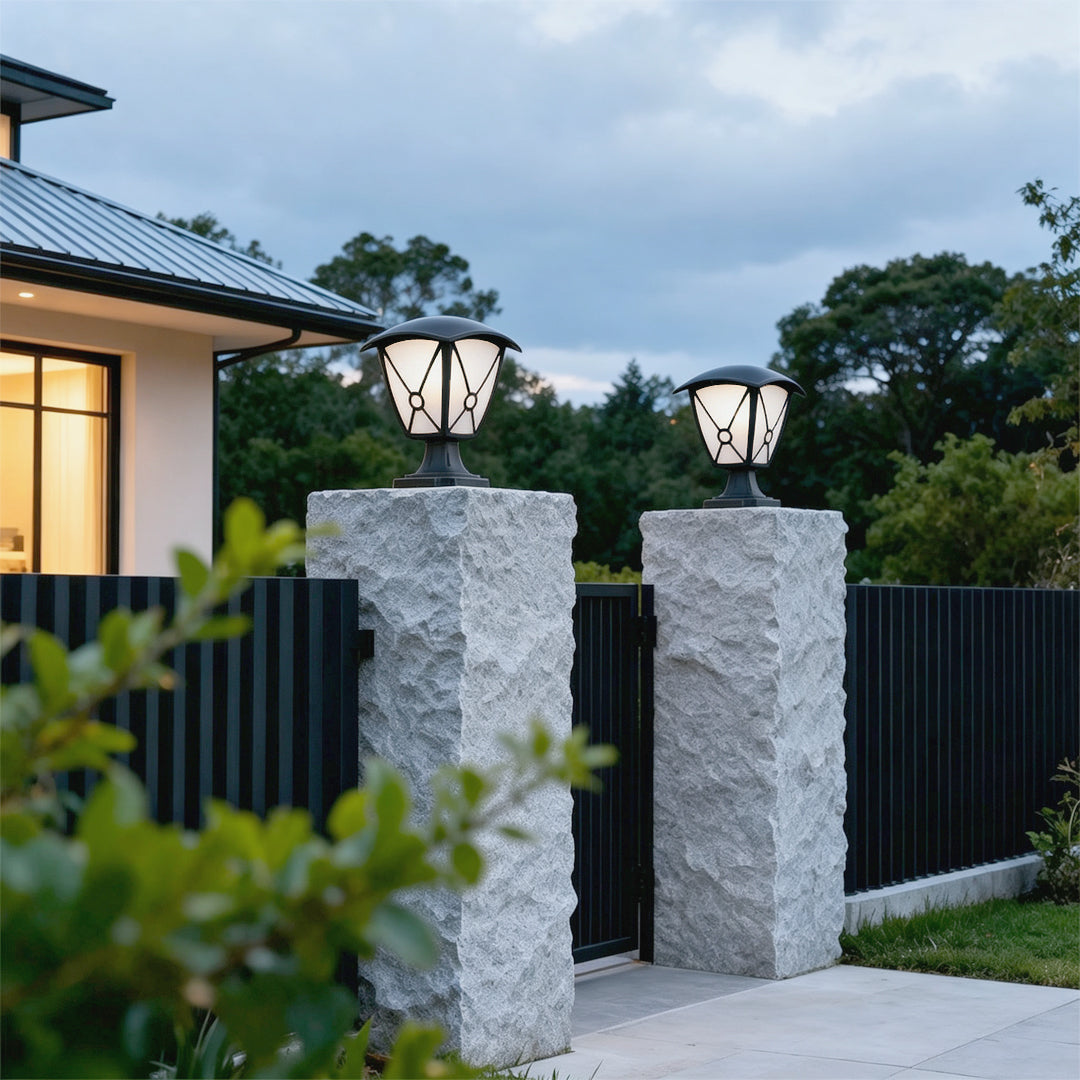 Aluminum pillar lights mounted on tall stone gate posts beside a modern residential entrance.