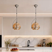 Amber glass globe pendant light installed above a modern kitchen island, providing warm ambient illumination.