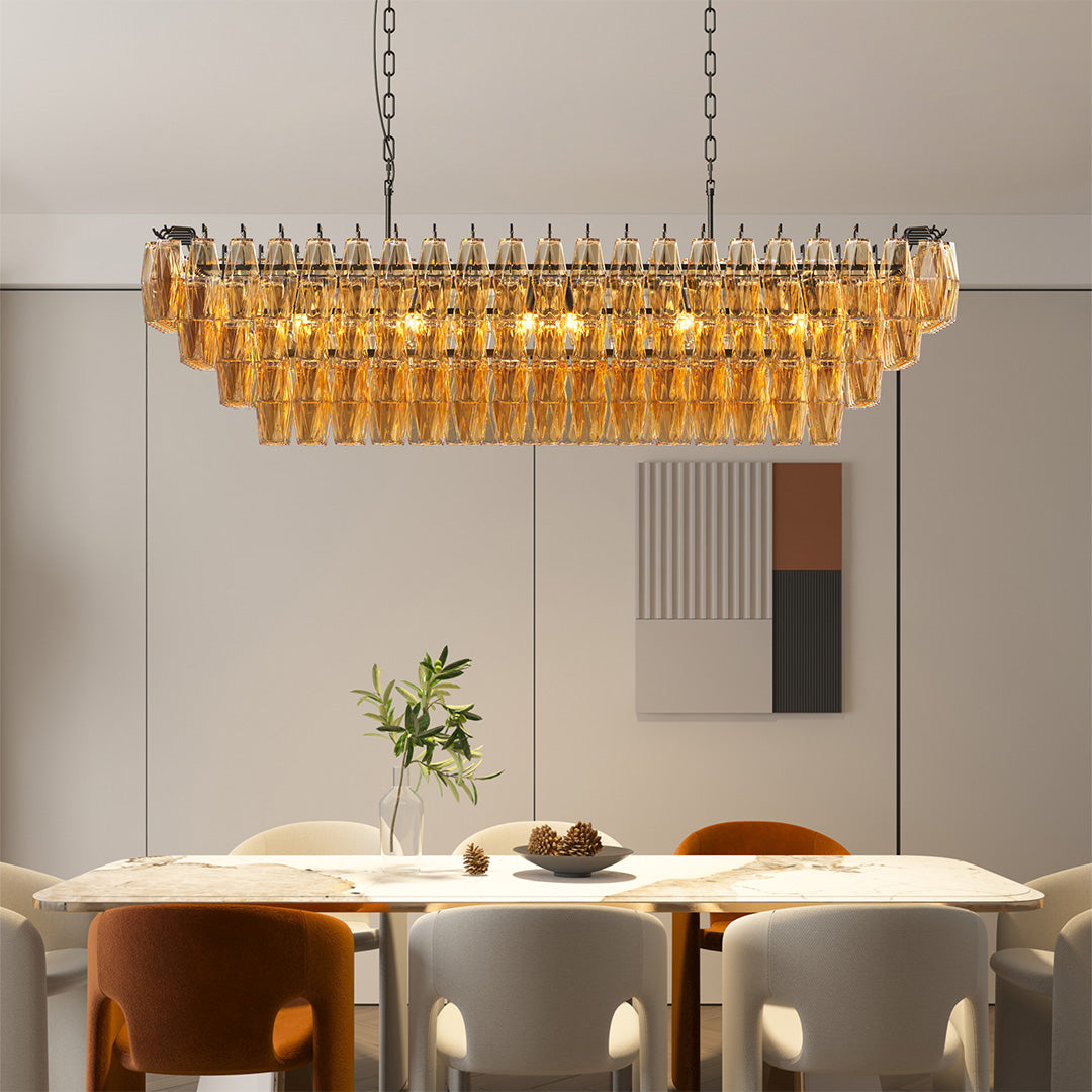 Rectangular amber glass pendant chandelier hanging over a large modern dining table.