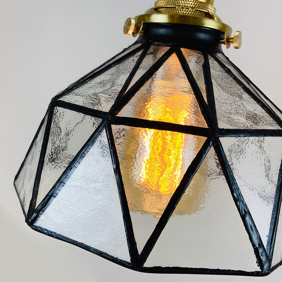 Amber indoor pendant light with a close-up of the geometric glass shade and brass fittings.