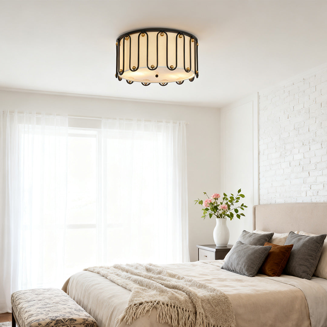 Drum ceiling light flush mount providing ambient light in a peaceful bedroom with layered bedding and white brick accent walls.