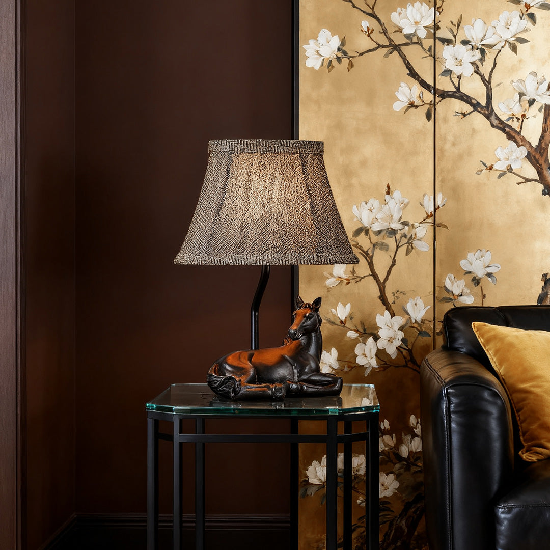 Table lamp horse on a small glass side table, providing ambient lighting in a richly decorated living room with a golden accent wall.