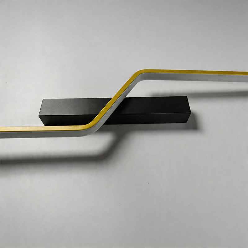 Macro view of the angular curve and gold stripe detail on a modern linear wall sconce fixture.