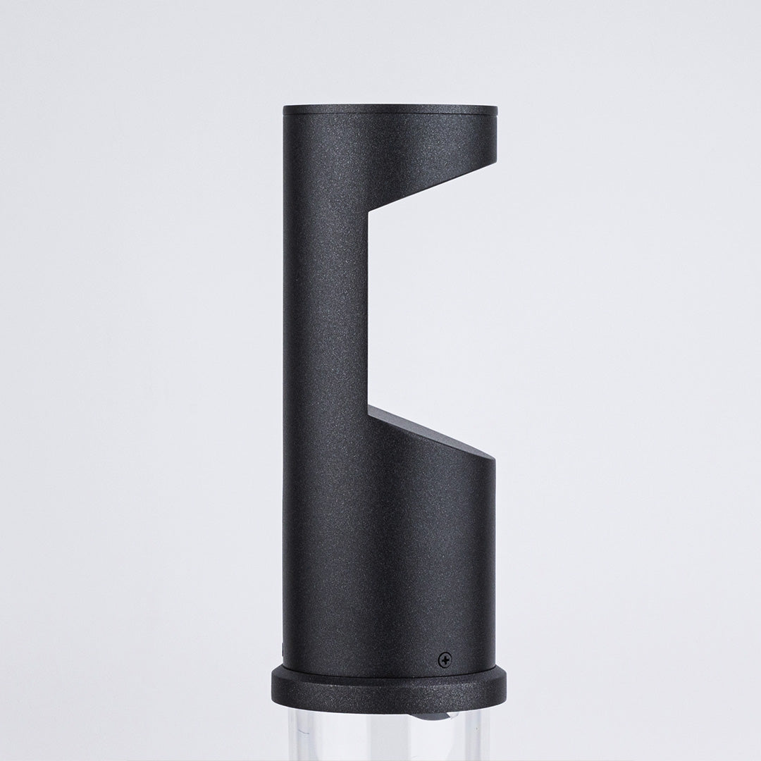 Black textured bollard light with angular geometric cut-out design for directional lighting