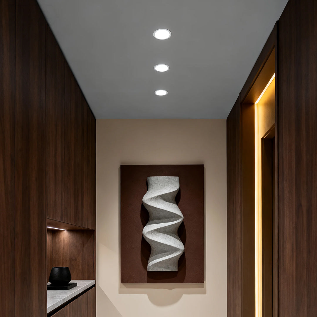 Anti glare downlights illuminating modern hallway with dark wood paneling and contemporary artwork