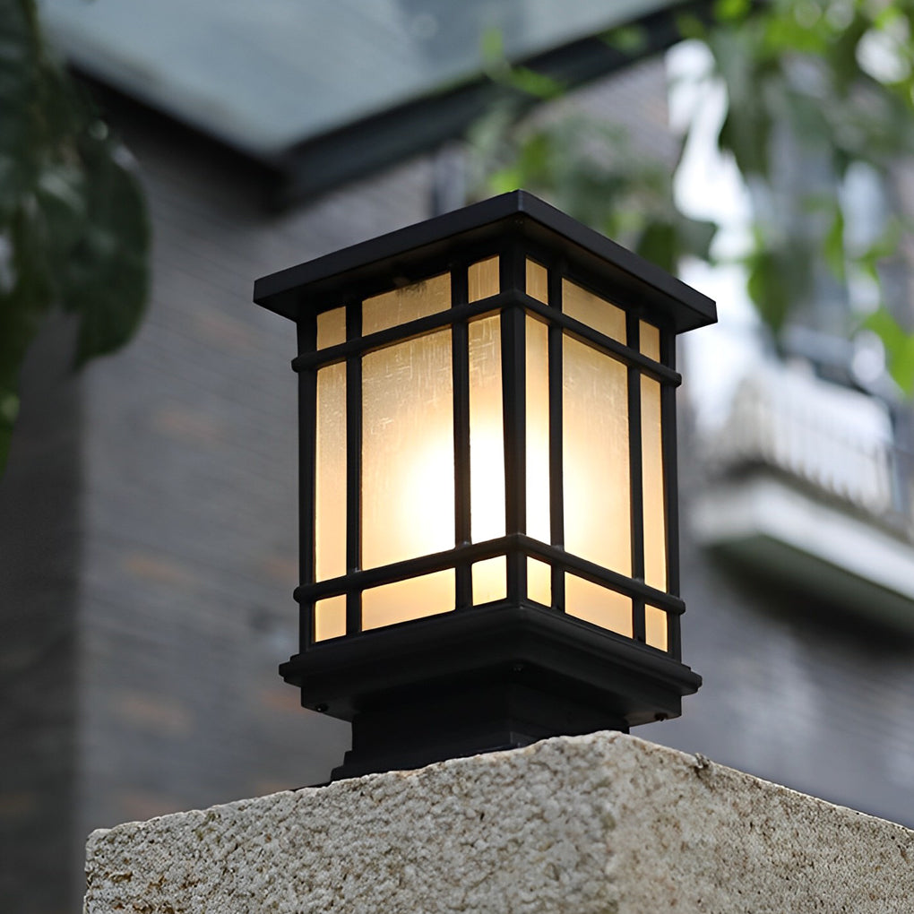 Antique cast iron street light casting a gentle light on a stone wall and plants.
