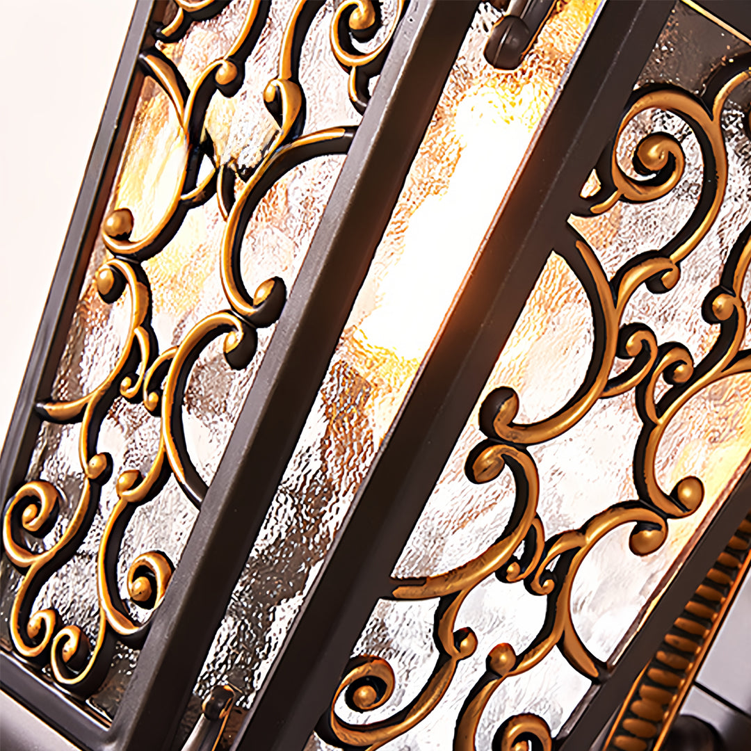 Antique outdoor wall sconce with ornate metal scrollwork mounted beside a glass door at dusk.