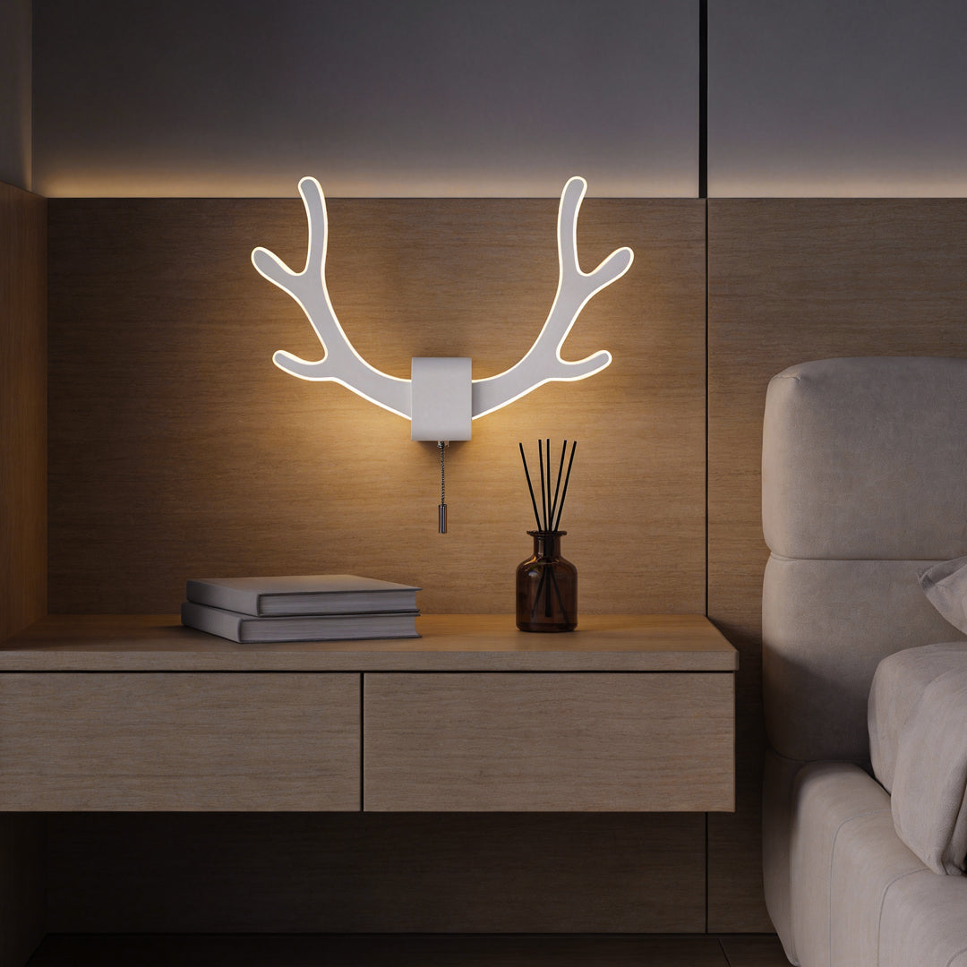 Antler wall sconce light mounted above a bedside cabinet, creating warm ambient lighting with a modern nature-inspired design.