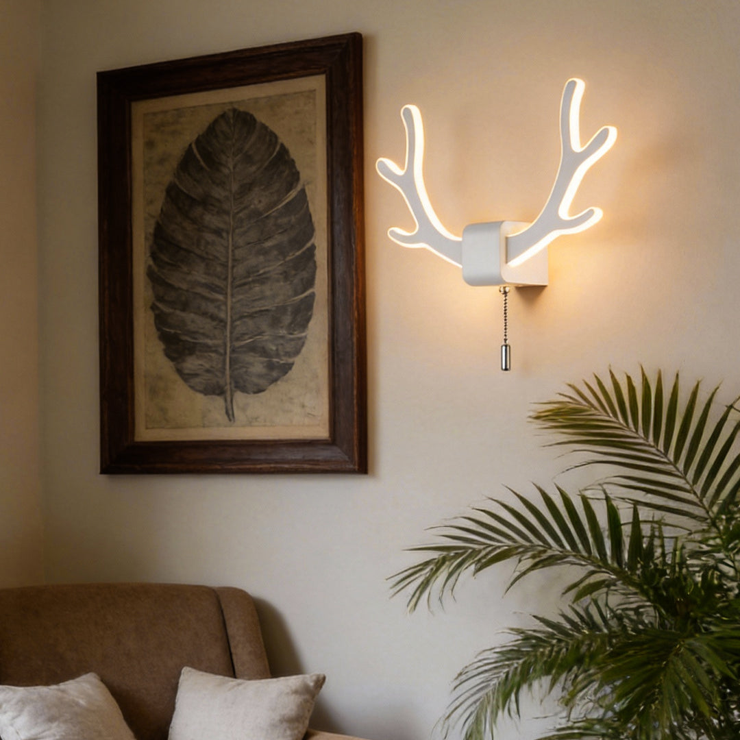 Antler wall sconce light installed in a living room corner, blending sculptural antler shape with soft warm illumination.