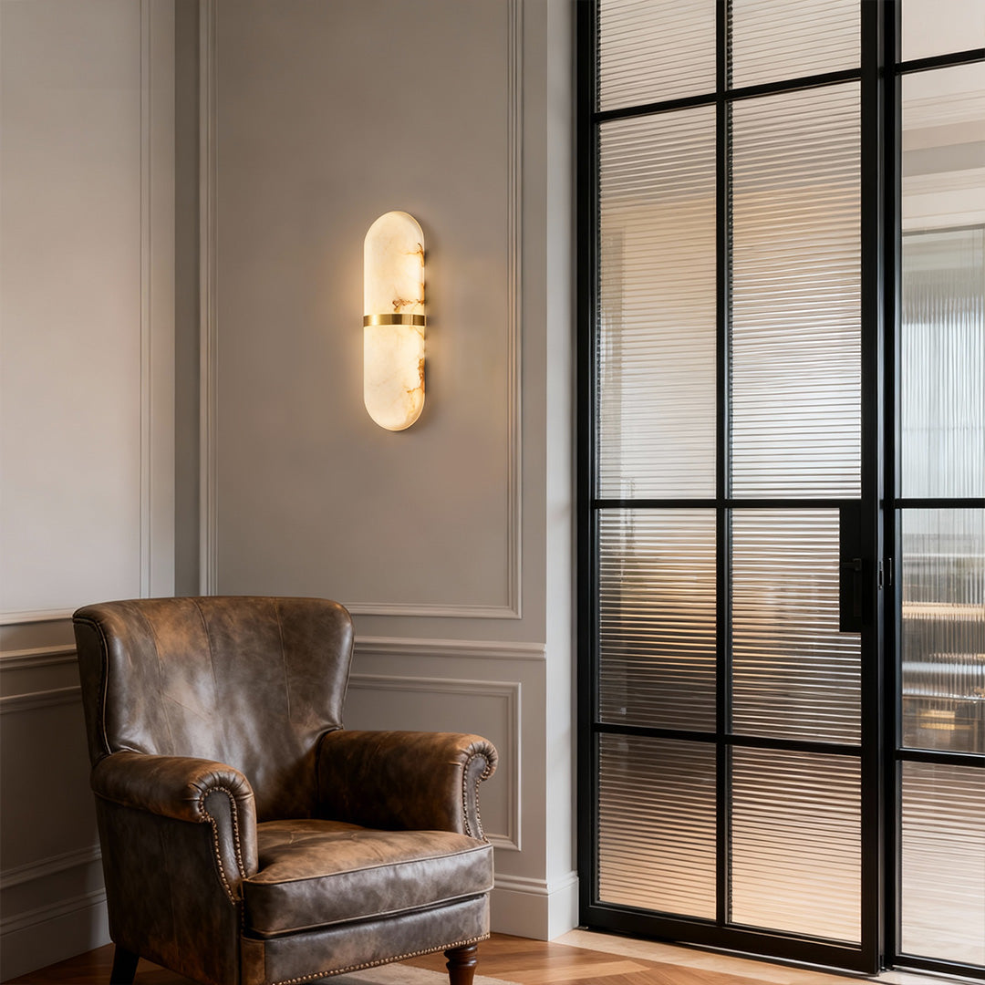 Architectural art wall lighting with glass shade chandelier styling illuminating modern entryway with glass partition and leather chair.