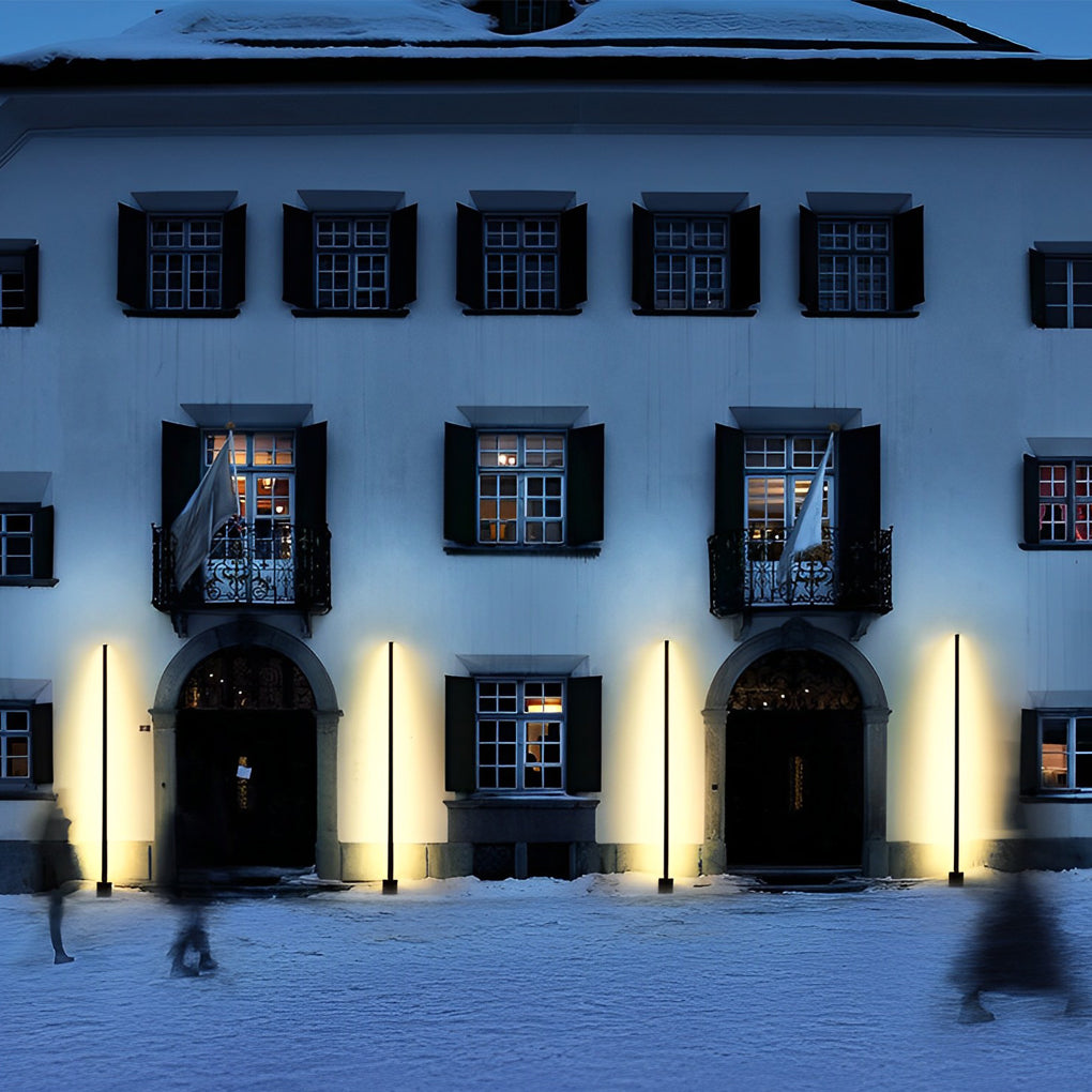 Architectural contemporary outdoor floor lamps illuminating a historic building facade at night.