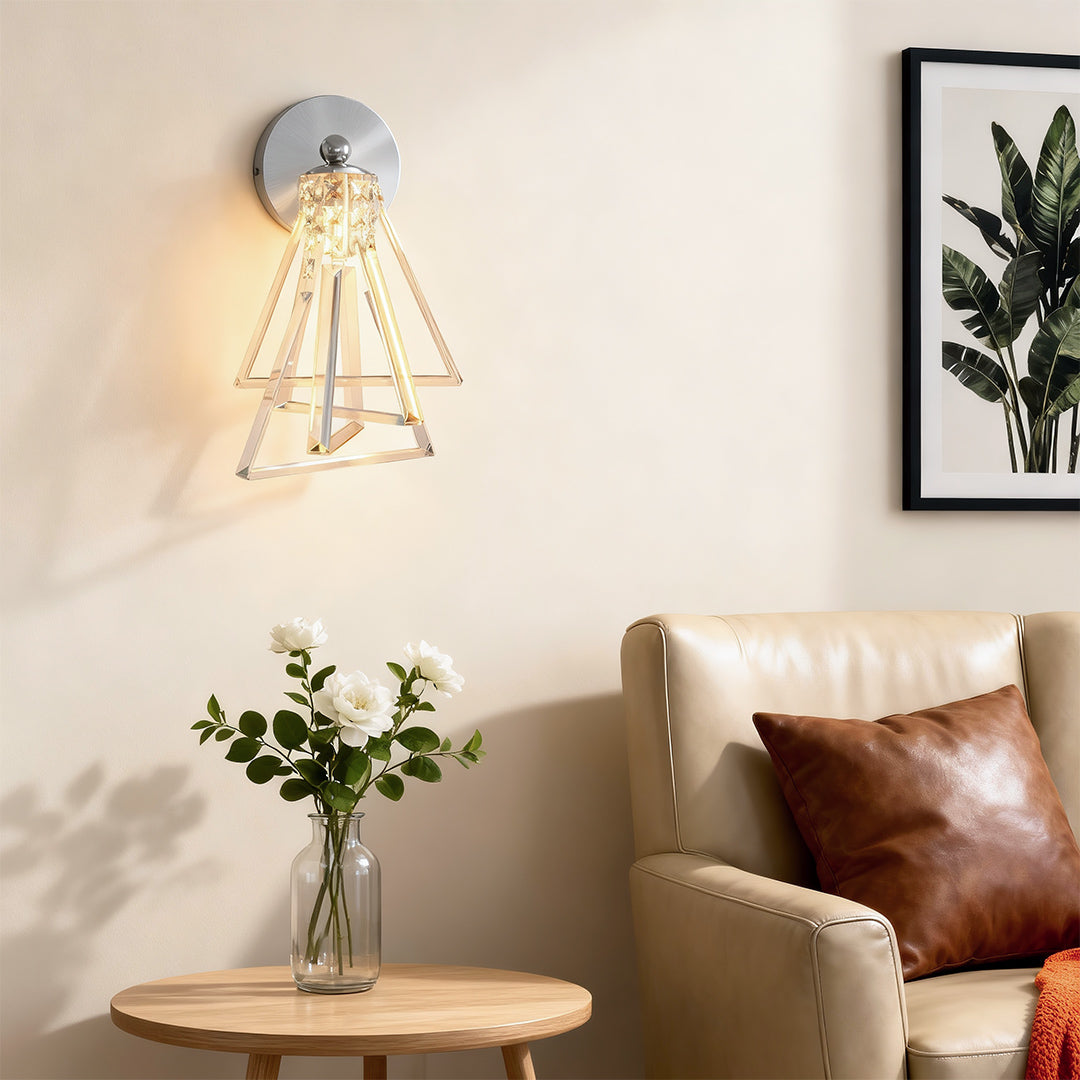 Architectural crystal wall lights with glass shade chandelier styling creating warm accent glow beside plush chair and round table.