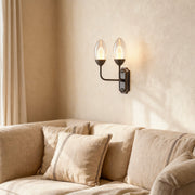 Architectural glass wall light with glass shade chandelier styling creating warm atmosphere in neutral-toned living room.