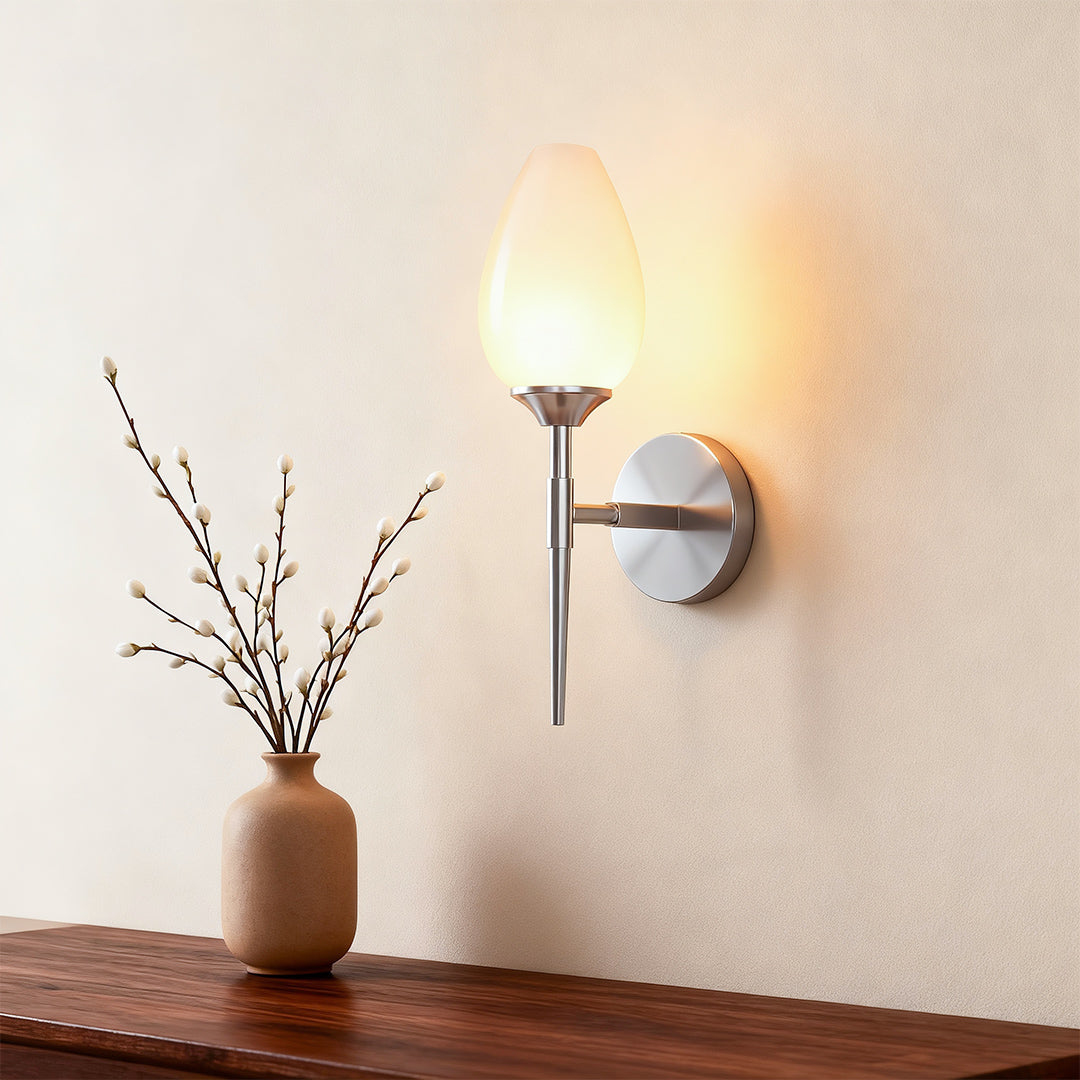 Architectural glass wall lights with glass shade chandelier styling creating warm accent glow on neutral wall beside vase.