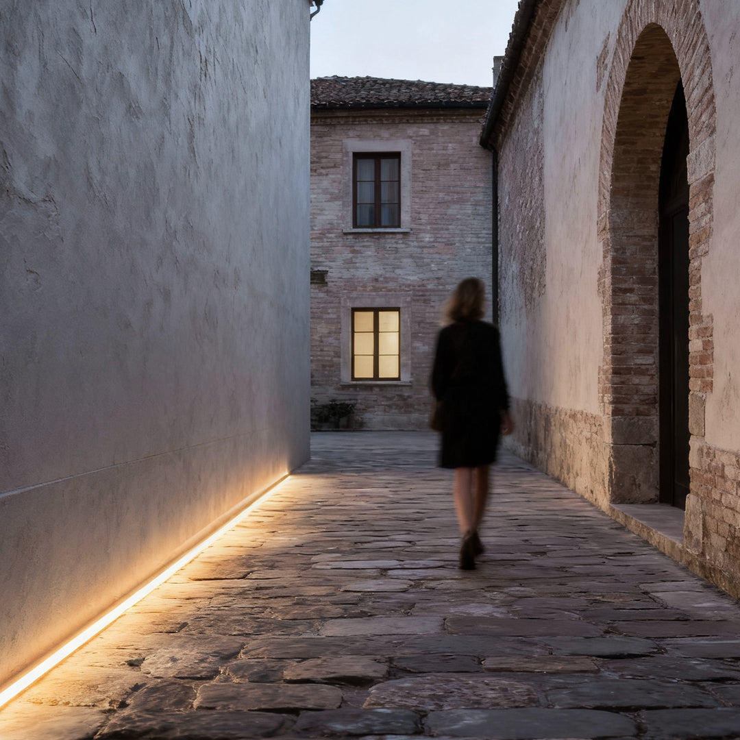 Architectural led strip lighting guiding a stone walkway with subtle linear light along historic walls.