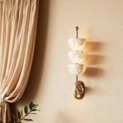 Architectural modern LED wall lights with glass shade chandelier aesthetic providing soft illumination beside flowing curtains.
