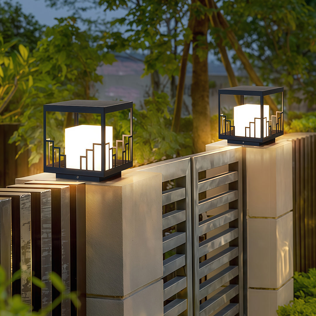 Architectural outdoor pillar light with glass shade chandelier aesthetic flanking modern home entrance at twilight.