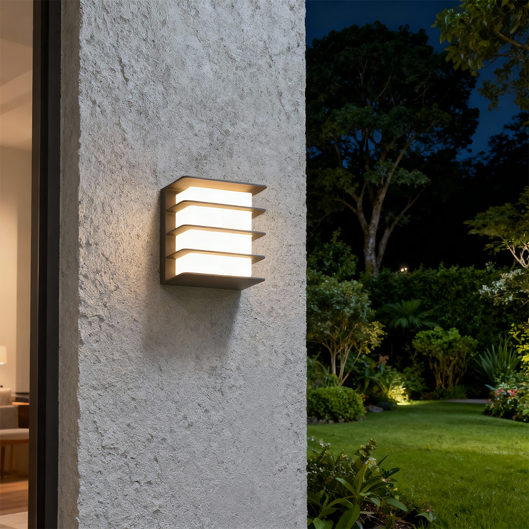 Architectural square LED wall lights featuring glass shade chandelier styling providing warm illumination on textured concrete exterior.