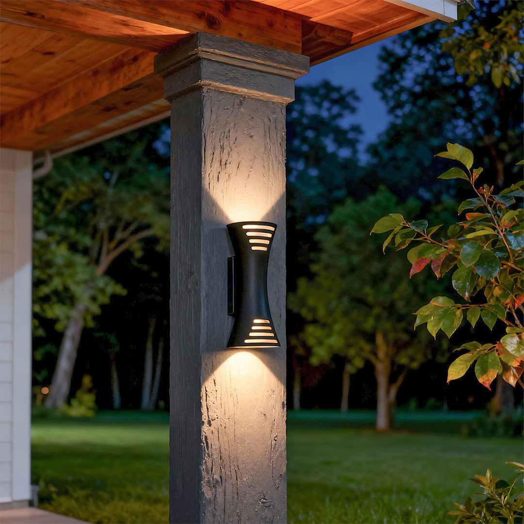 Architectural up down lighting wall sconce featuring glass shade chandelier styling providing warm uplighting and downlighting on stone column.