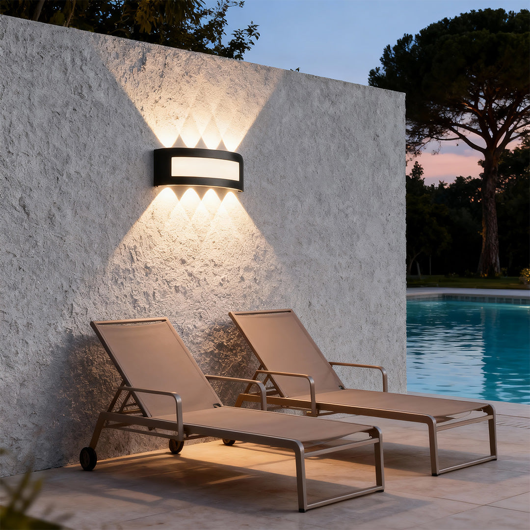 Architectural up down wall lights featuring glass shade chandelier styling providing ambient poolside illumination at twilight.