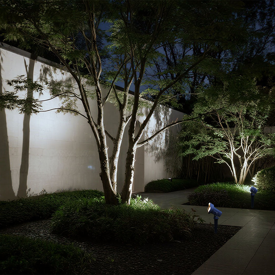 Architectural uplighting highlighting trees and modern building elements in contemporary landscape design