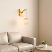 Architectural wall mounted pendant light with glass shade chandelier styling creating warm glow beside neutral sofa in modern interior.