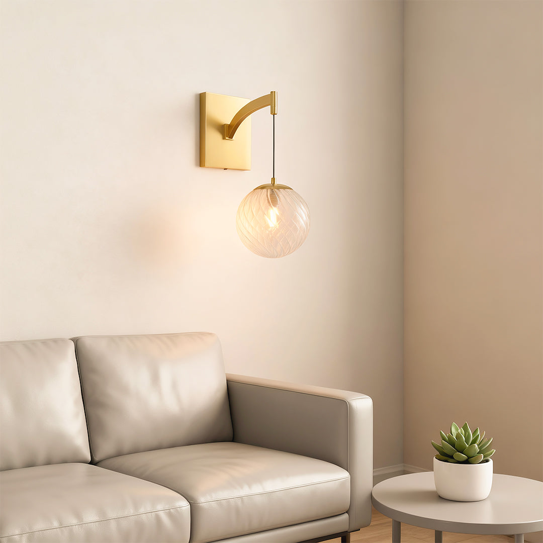 Architectural wall mounted pendant light with glass shade chandelier styling creating warm glow beside neutral sofa in modern interior.