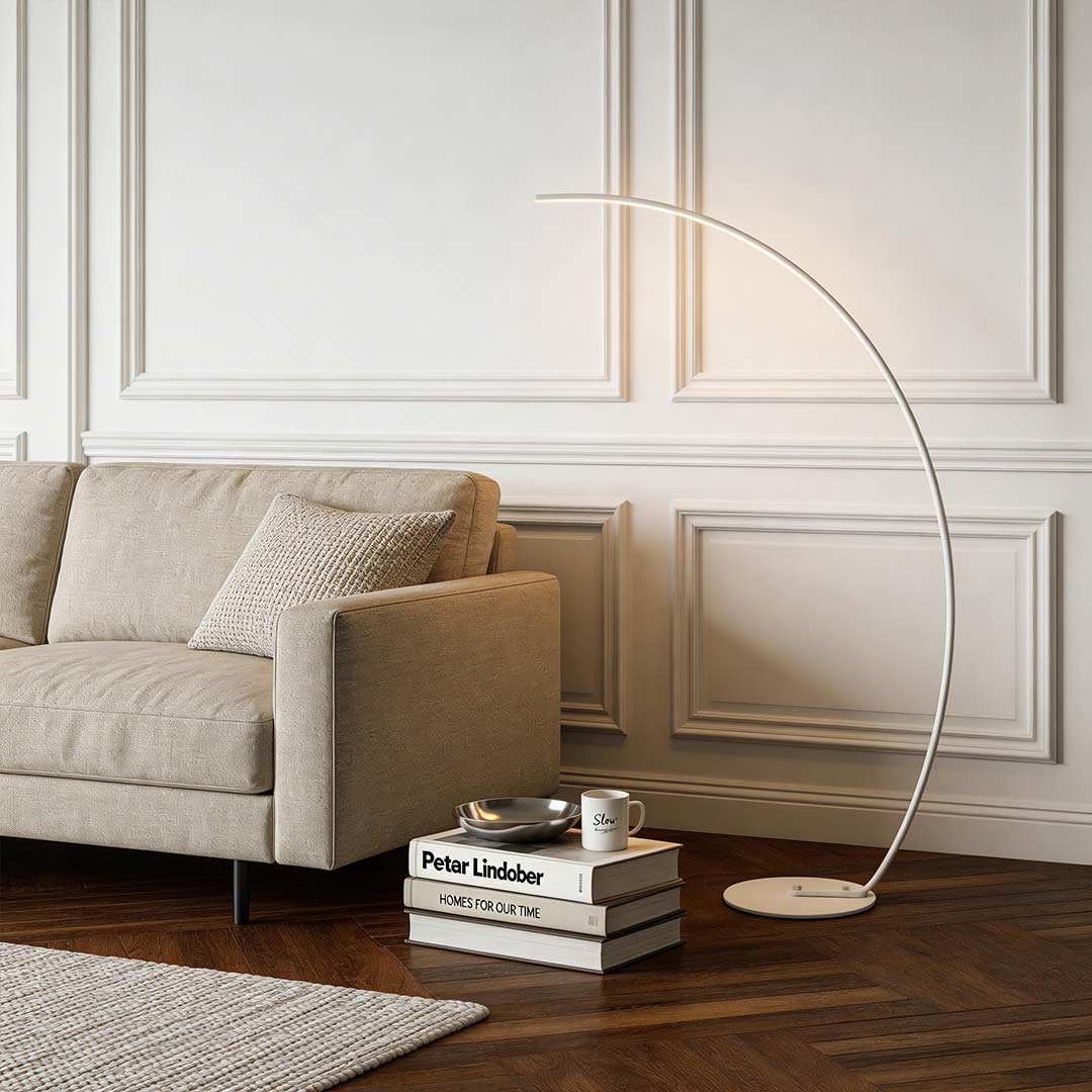 Arcing floor lamp with a minimalist design, providing soft light above a contemporary sofa.