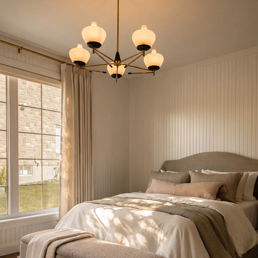 Art deco vintage chandelier hanging above a bed in a bright neutral bedroom with soft natural light.