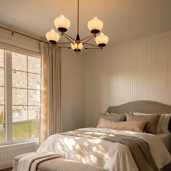 Art deco vintage chandelier hanging above a bed in a bright neutral bedroom with soft natural light.