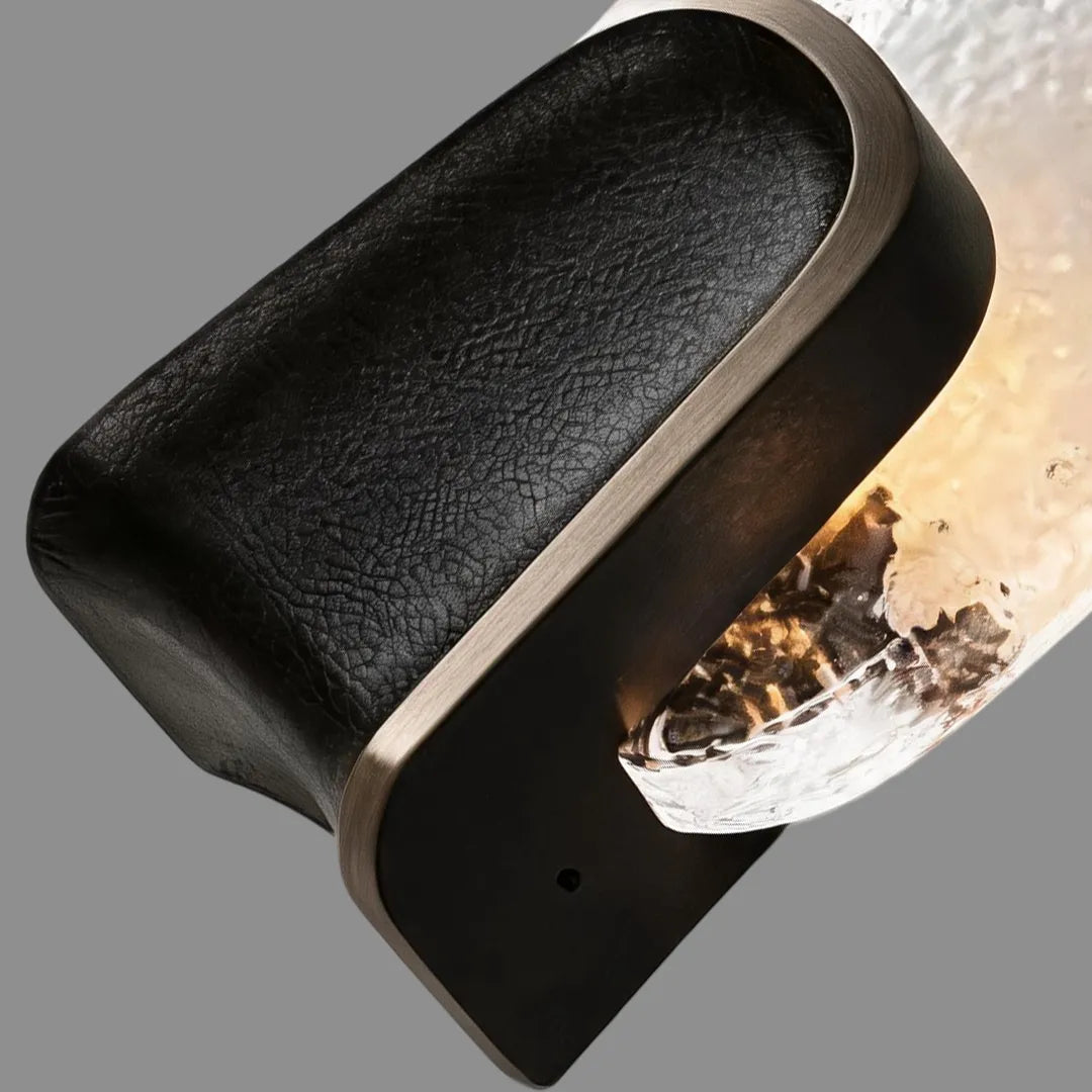 Close-up of art deco wall sconce lighting showing the curved black metal body and textured glass shade.