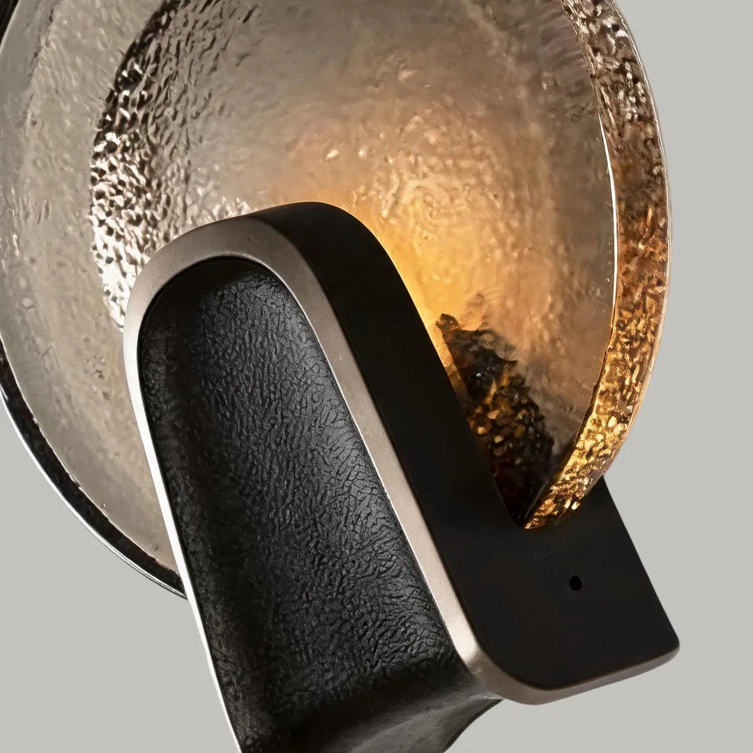 Close-up of art deco wall sconce lighting with a black finish and smoky gray round glass shade.