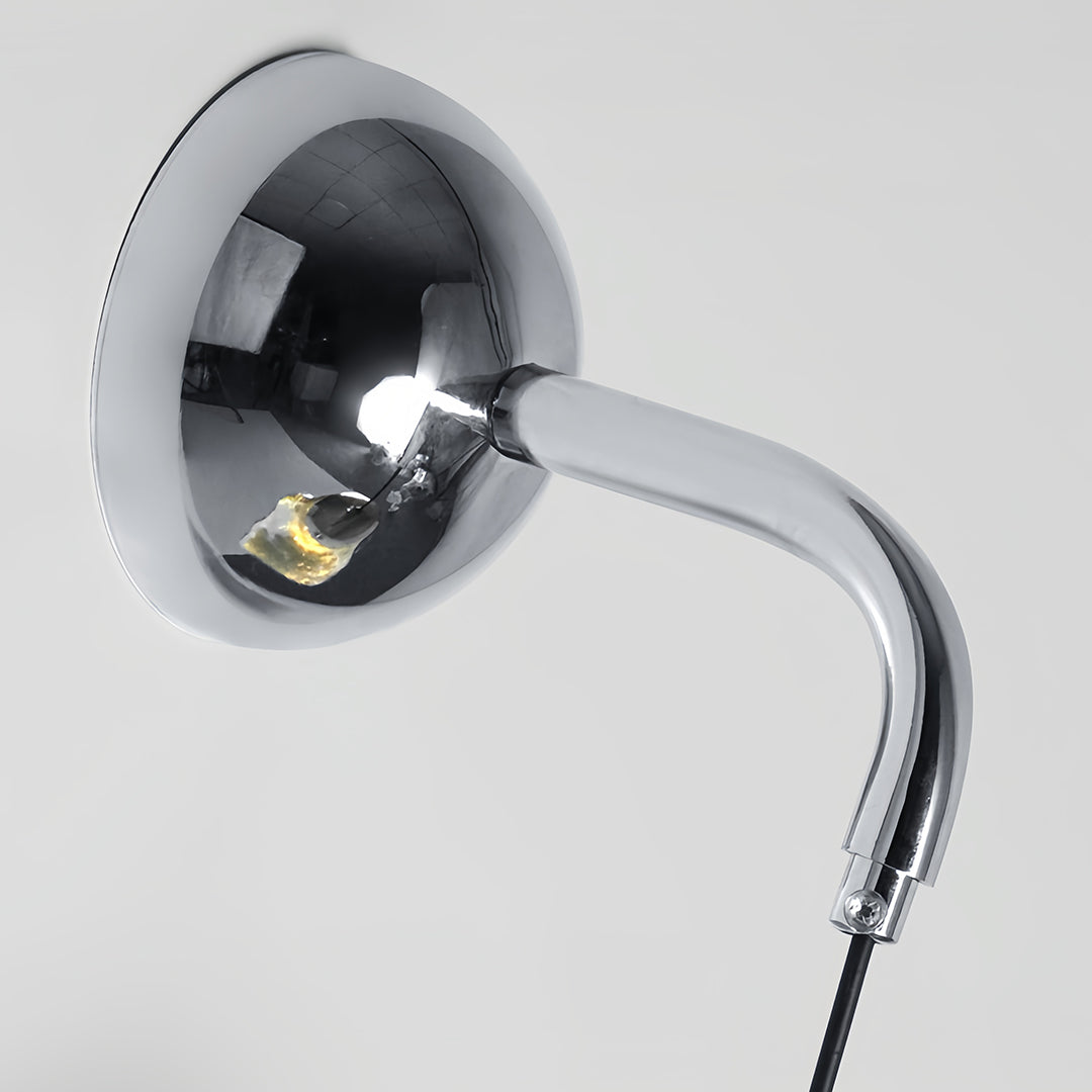 Close-up of art deco wall sconce lighting showing chrome gooseneck arm and reflective dome detail