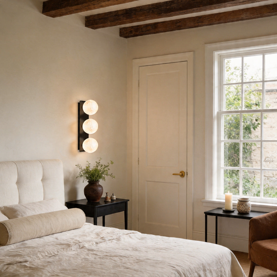 Vertical art glass wall sconce lighting in a warm bedroom setting.