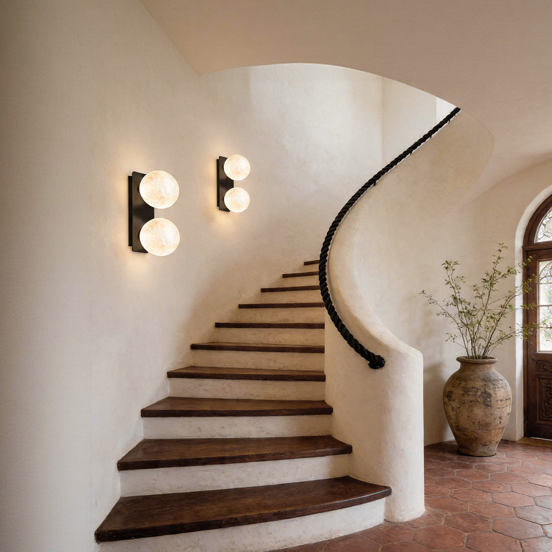 Modern art glass wall sconces mounted beside a curved staircase.