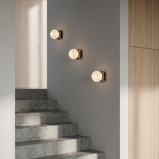 Art glass wall sconces installed along a modern staircase wall.