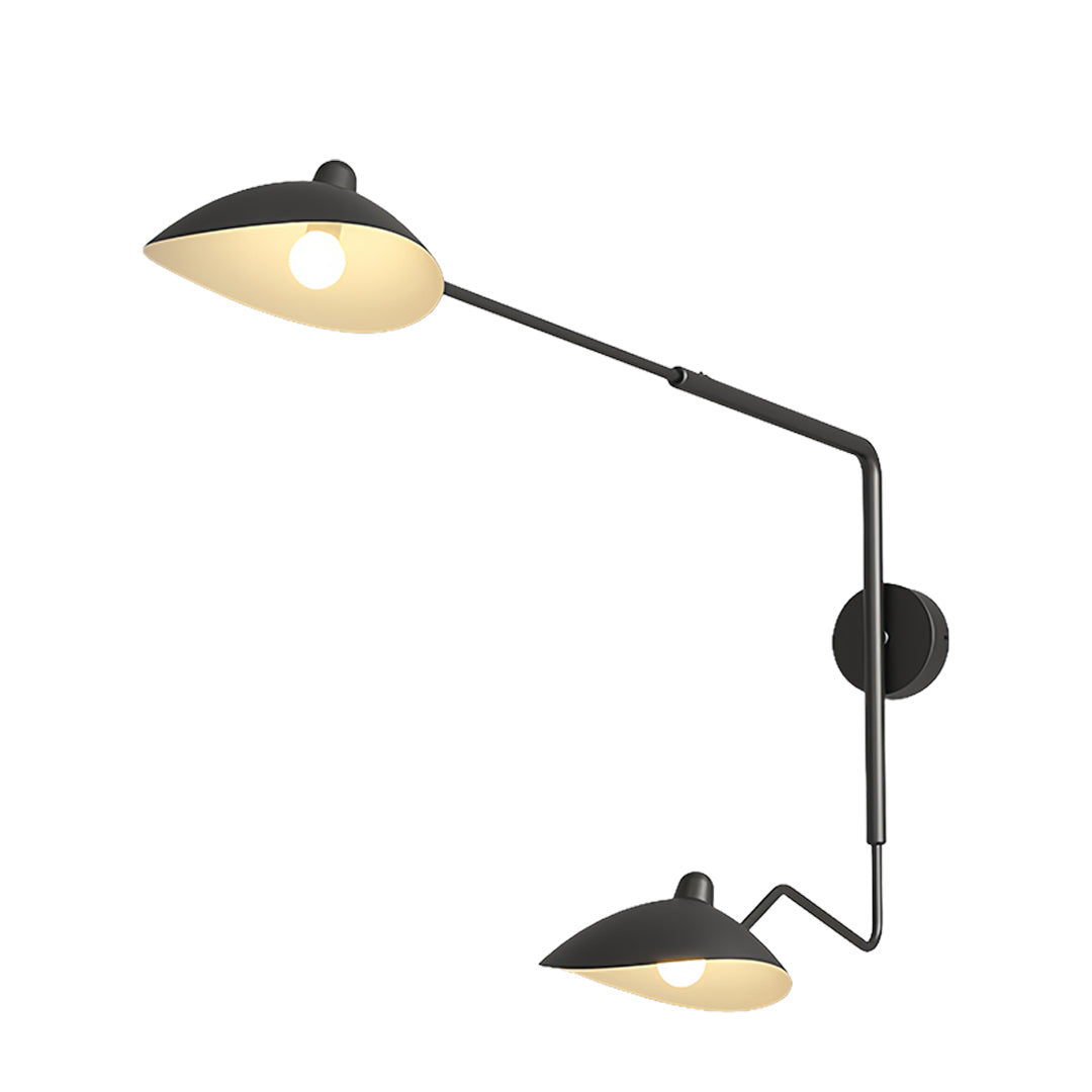 Articulated swing arm wall light installed above a bedside area, offering adjustable reading light with a minimalist, black metal design.