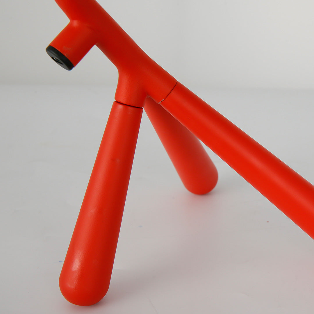 Bright red three legged table lamp with articulated joints for versatile positioning and task lighting