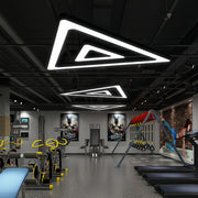 Multiple black modern chandeliers creating an artistic lighting display in an industrial interior.