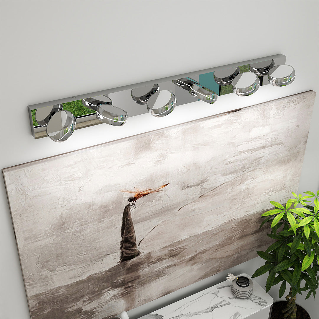 Artistic chrome bathroom vanity light featuring glass shade chandelier styling illuminating beach-themed decorative mirror wall.