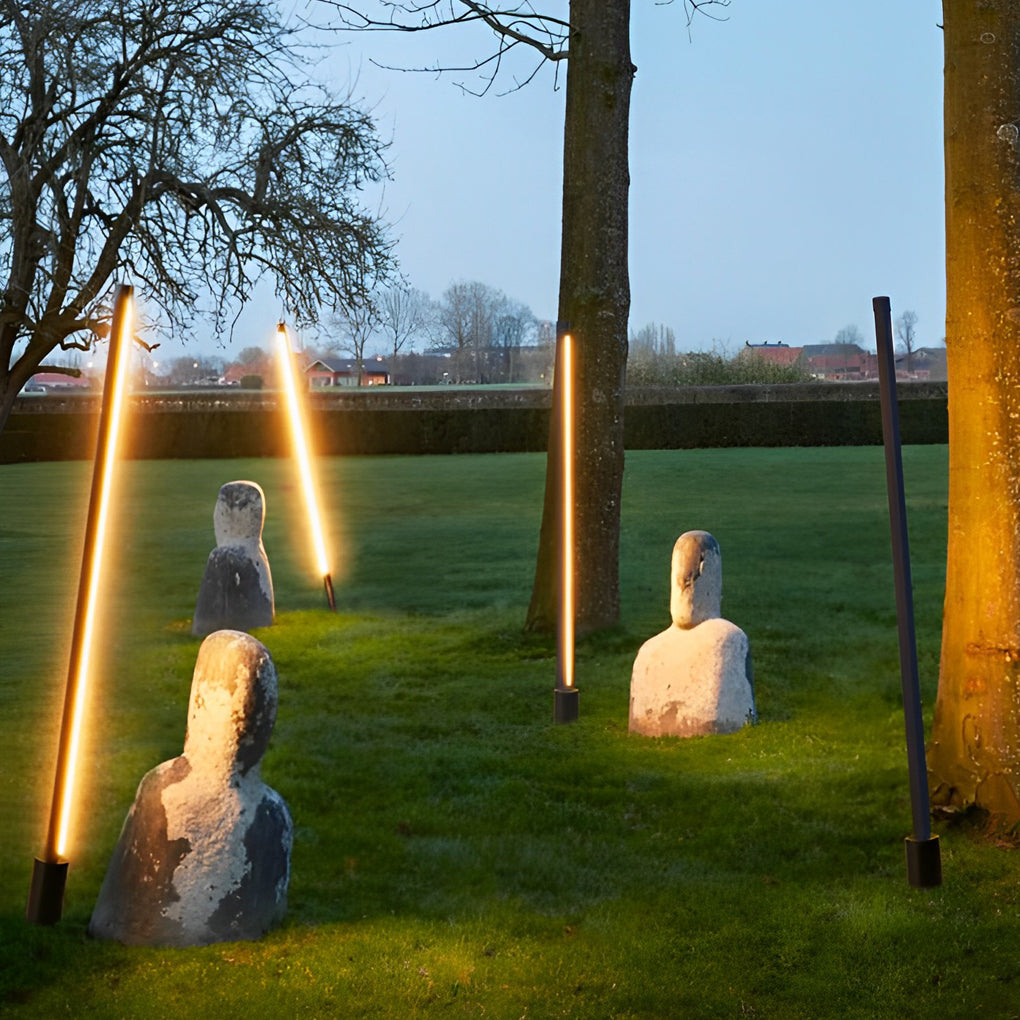Artistic contemporary outdoor floor lamps installed at angles in a landscaped lawn setting.