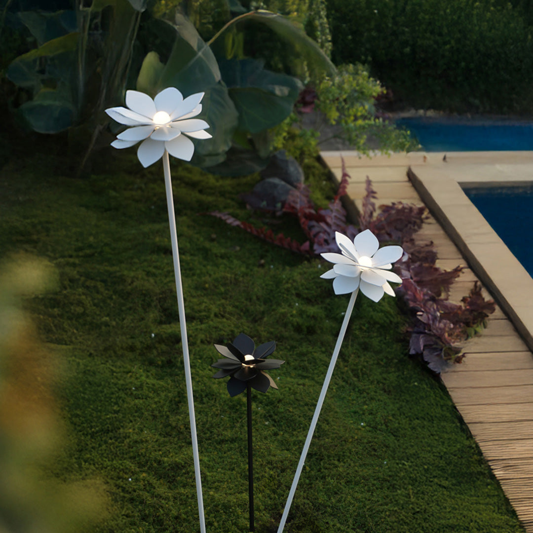 Artistic flower landscape garden lights arranged near water feature with lush green foliage backdrop