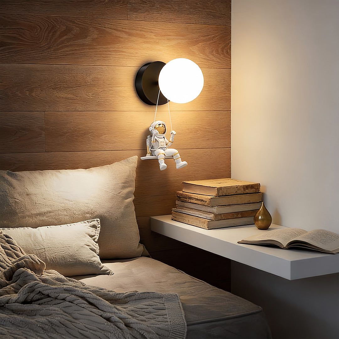 Astronaut wall light illuminating a modern bedroom with a gray headboard and soft bedding.
