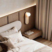Ball wall lamp with a minimalist wooden design, providing soft illumination in a cozy bedroom.
