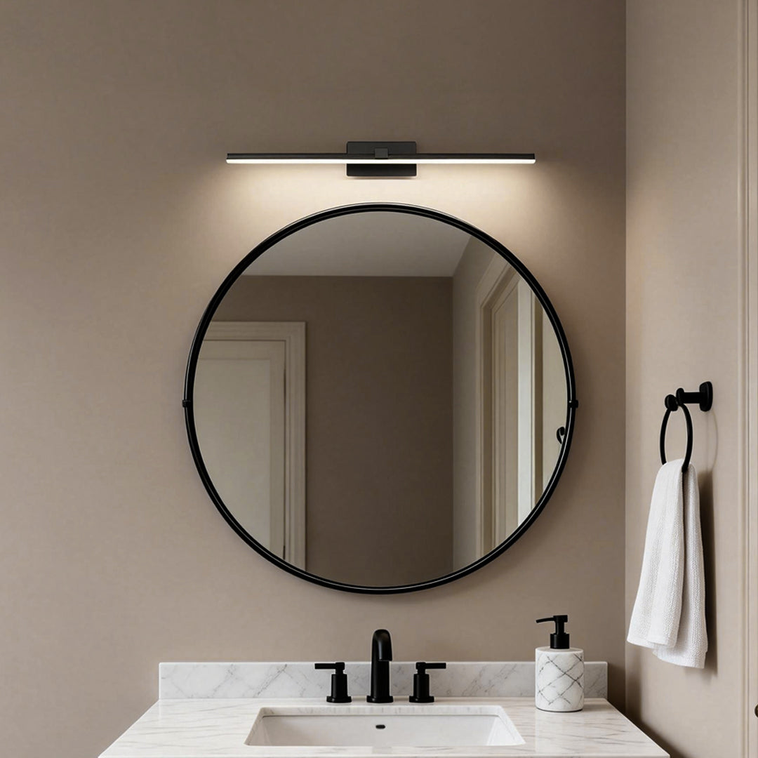 Modern bathroom featuring round mirror illuminated by bathroom lights above vanity with soft ambient glow.